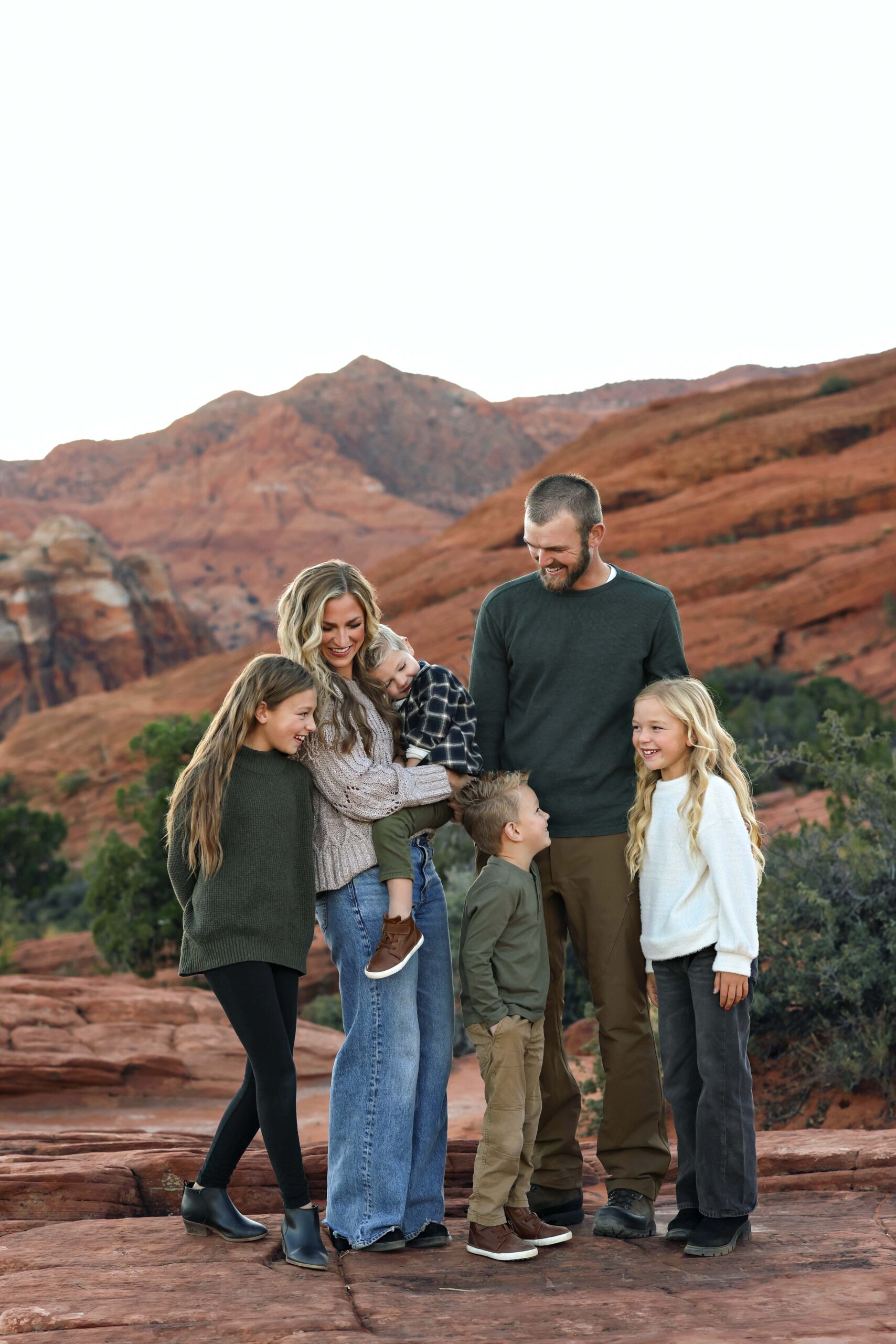 Family standing together in front of red rock formations at Snow Canyon State Park during golden hour