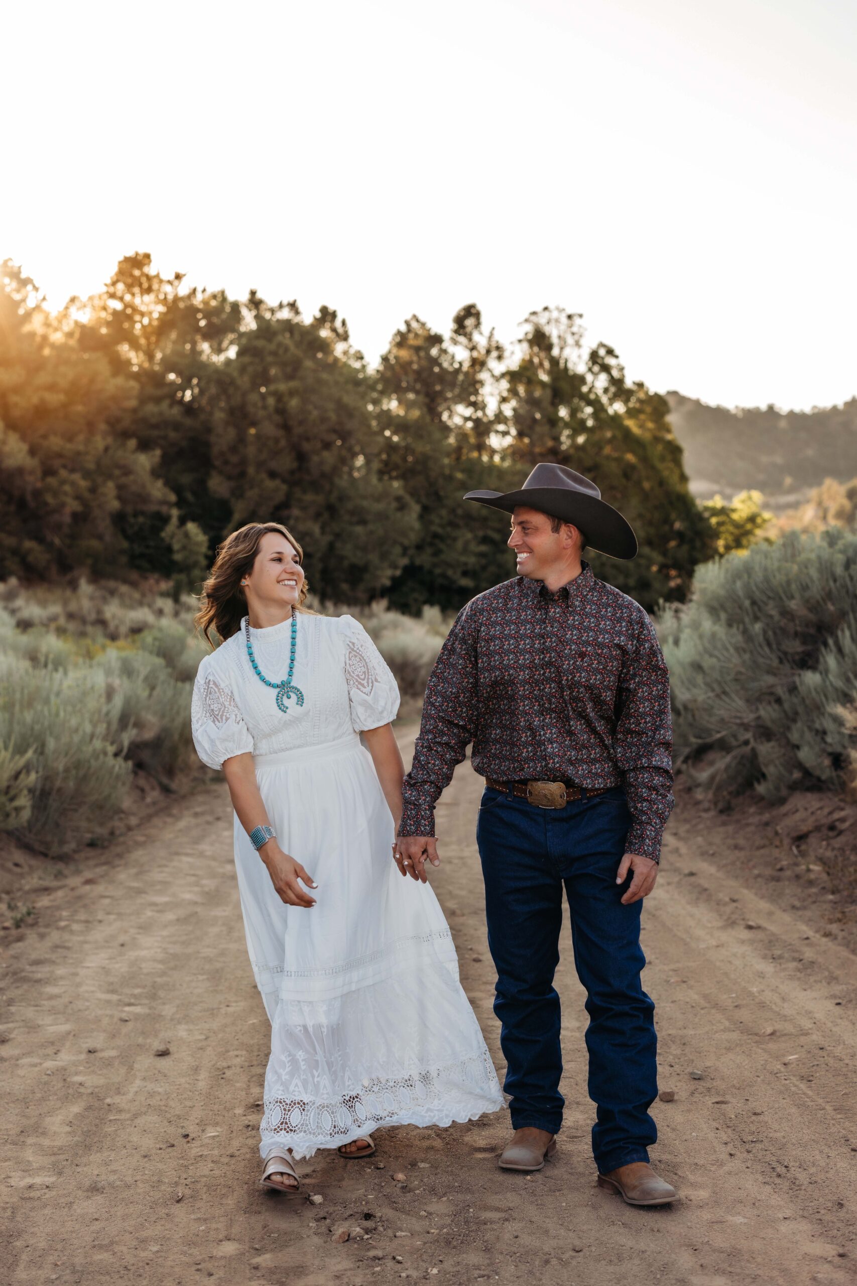 A couple walks down a country road while laughing and holding hands with each other